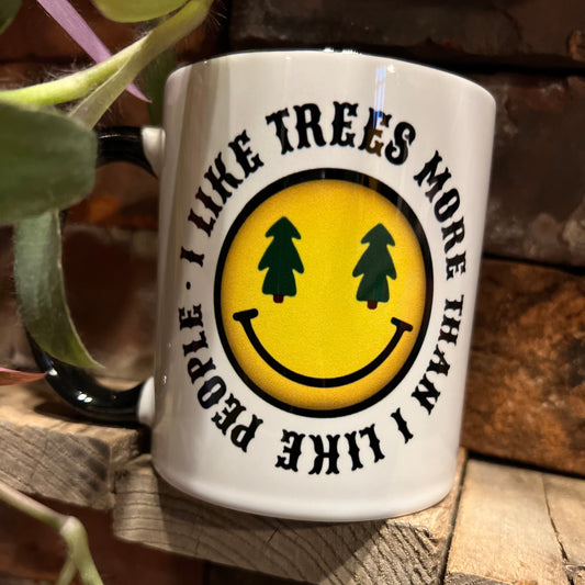 White mug with a yellow smiley face and text on a wooden background